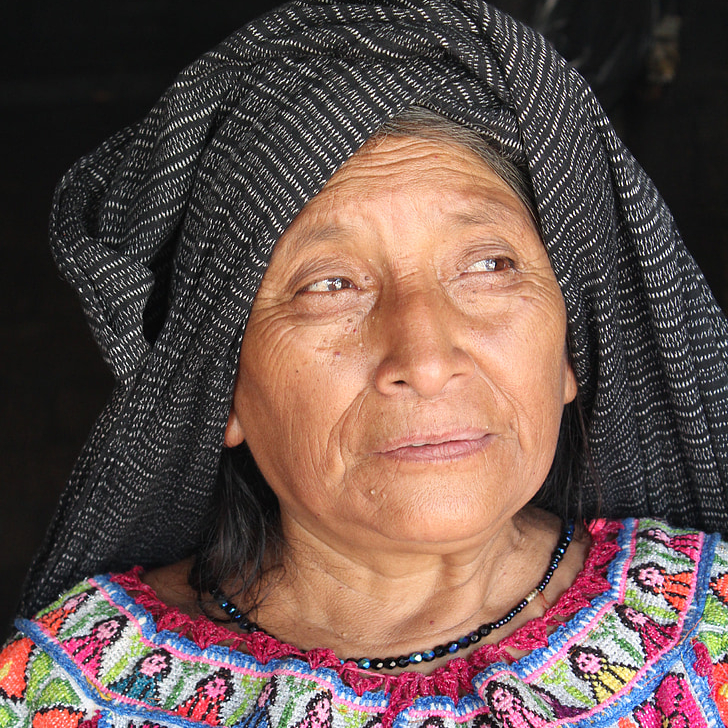 A woman wearing a head scarf and a colorful shirt.