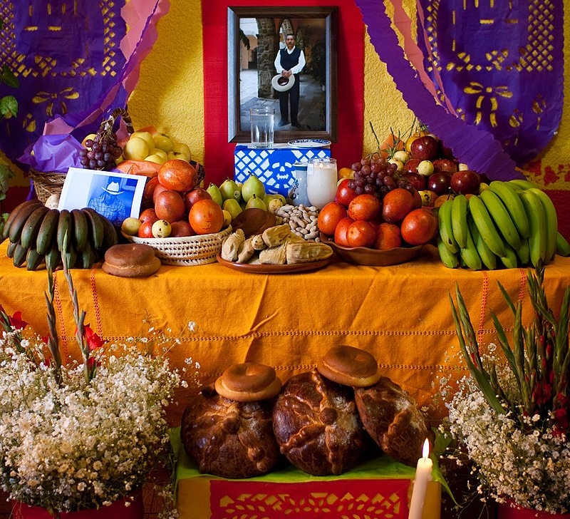 A memorial with food, drinks, and framed pictures on a table.